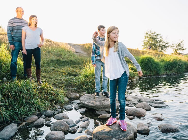 A family hiking along the Bow River near Seton Ridge.