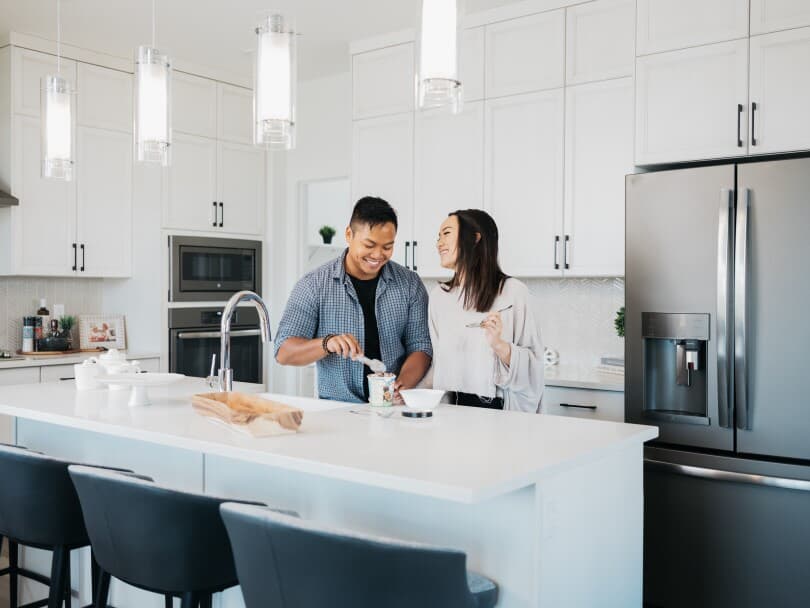 Couple eating ice cream in the kitchen of their Brookfield Residential home in Edmonton, AB