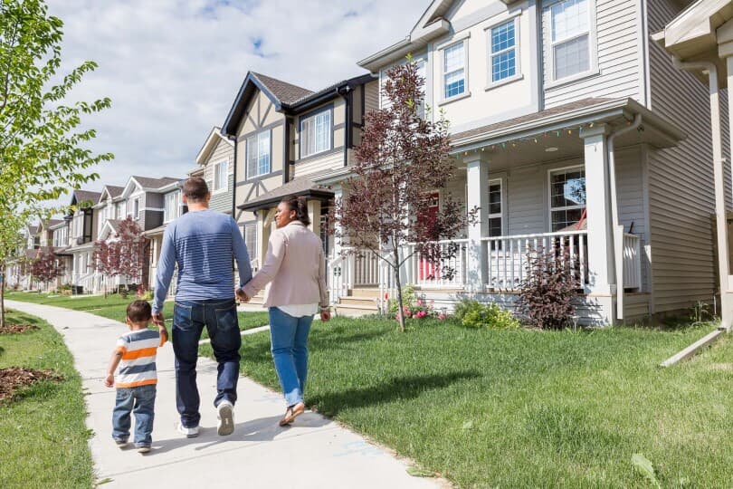 Family holding hands and walking on a sidewalk in their Brookfield Residential community in Edmonton, AB