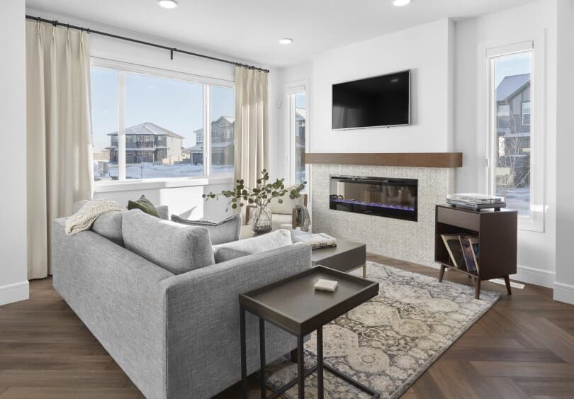 Fireplace and grey couch in the great room at Asher at The Orchards in Edmonton, AB