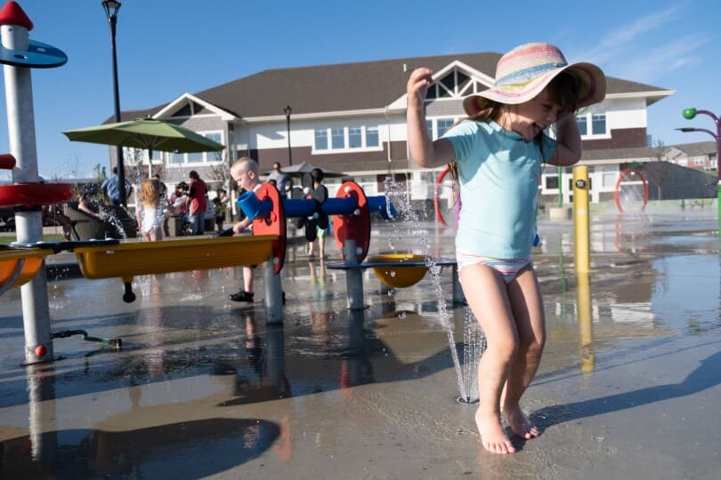 Kids playing in the spray park at The Orchards in Edmonton, AB by Brookfield Residential