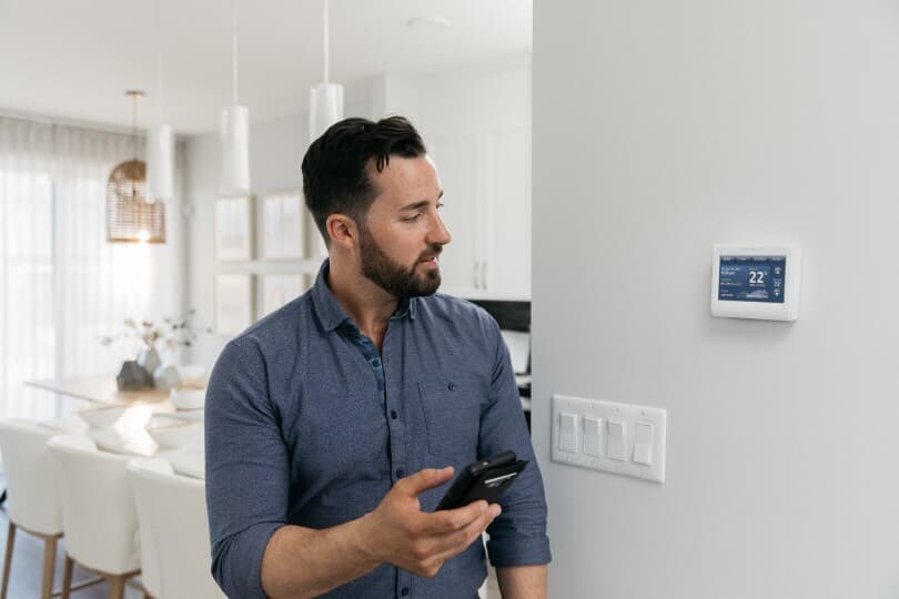 Man controlling his thermostat from his phone in his Brookfield Residential home in Edmonton