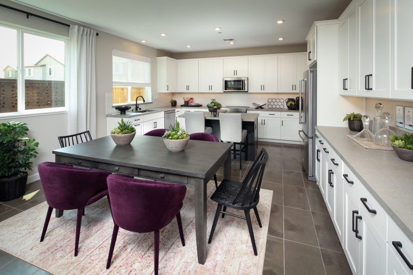 Dining area with purple chairs and white kitchen in Residence 5 at Chandler in Brentwood CA
