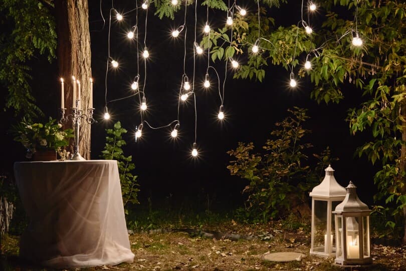 Outdoor wedding setup with string lights and lanterns