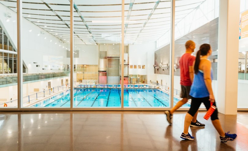 Couple walking in front of the pool at the Brookfield Residential YMCA at Seton in Calgary AB