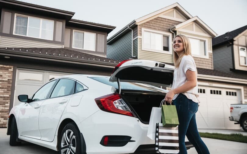 Young woman unloading shopping bags from her car in the Edgemont community in Edmonton AB