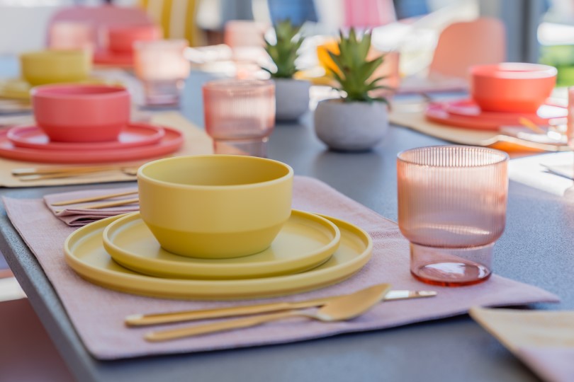 Close-up of a set dining table with bowls, plates, glasses, and silverware outdoors