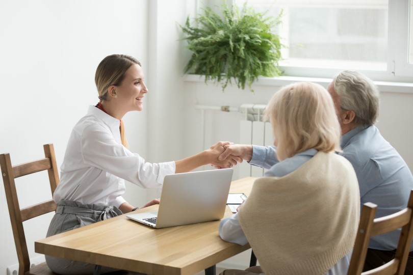 Concept of a family meeting; adult daughter shaking hands with an older father