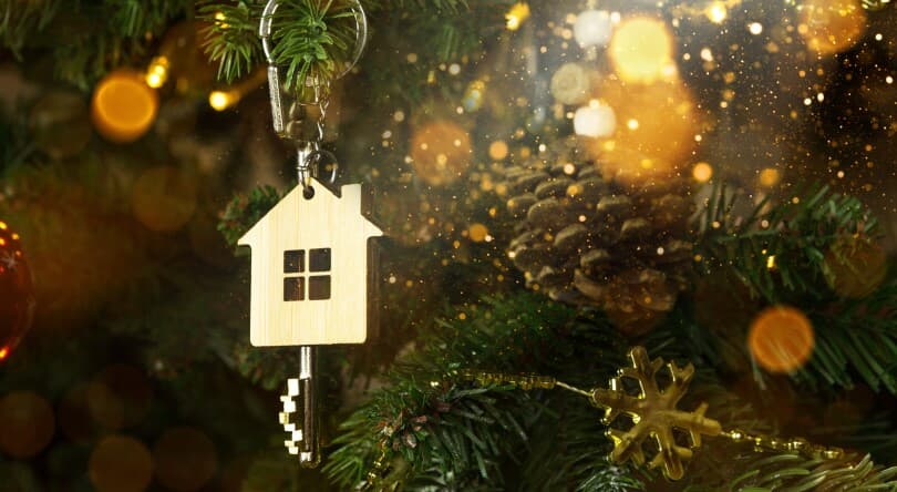 Key to the house with a keychain is hanging on the Christmas tree