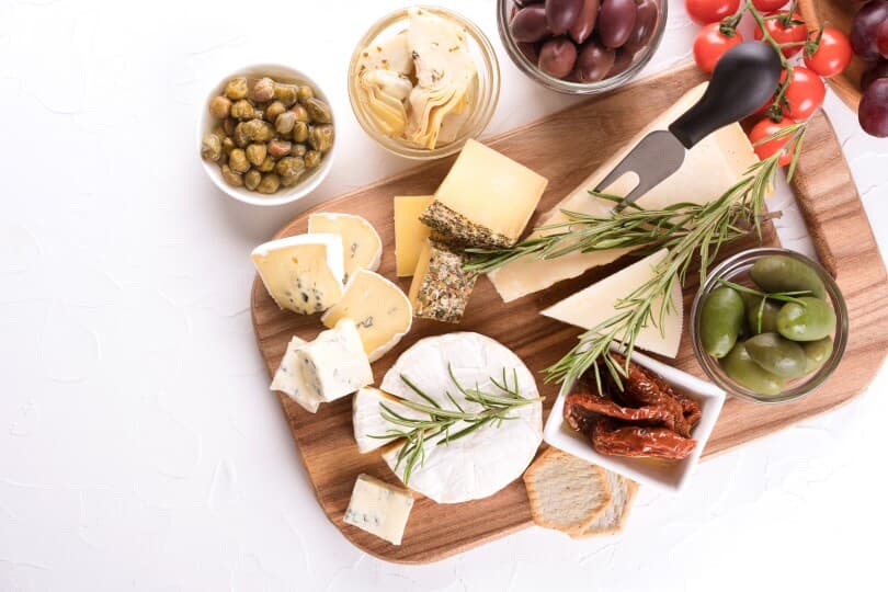 Charcuterie board with cheese slices and assortment of traditional Italian antipasti