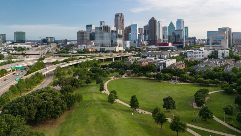 Traffic moving along green parks on North Central Expressway to Dallas Downtown TX