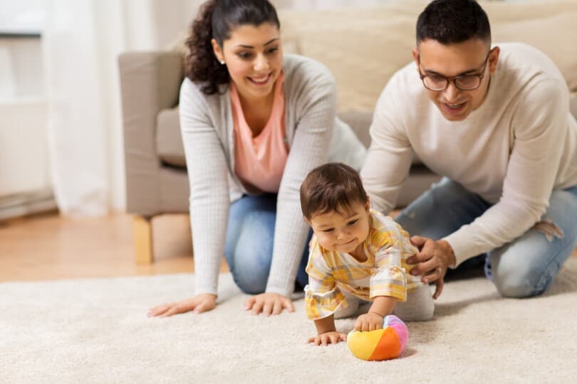 Mother and father playing with their baby crawling on the floor
