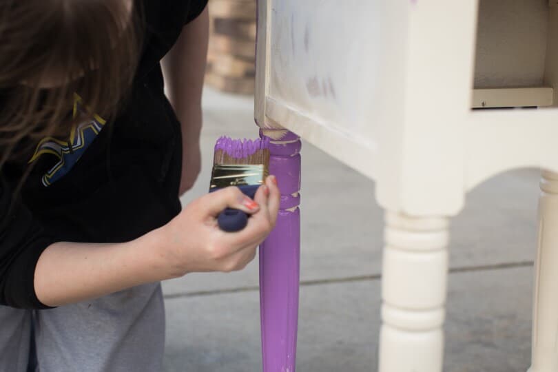Woman painting wooden furniture purple