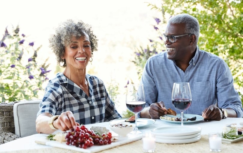 Older couple enjoying wine and grapes outside at Heritage Shores in Bridgeville DE by Brookfield Residential