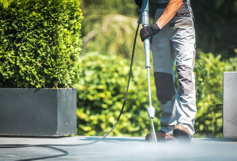 Man pressure washing a backyard patio