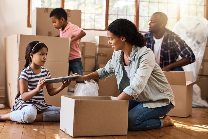 A family unpacks boxes on living room floor after moving
