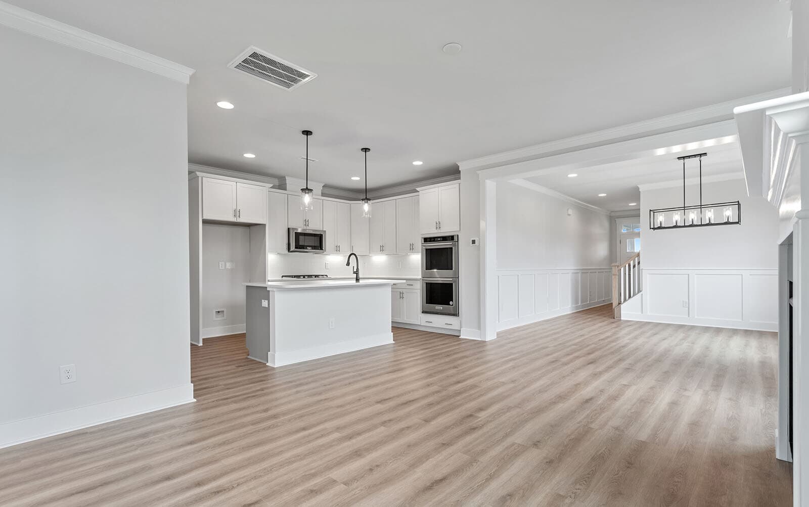 The kitchen open to the great room and dining room of the Mason at Wendell Falls by Brookfield Residential