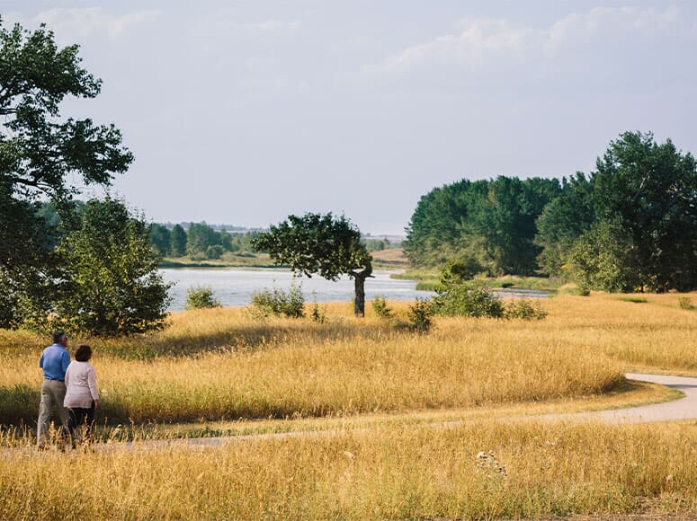 A couple walks along the Bow River pathway.