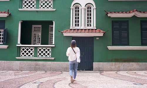 女性が後ろ向きに建物のの前に立っている