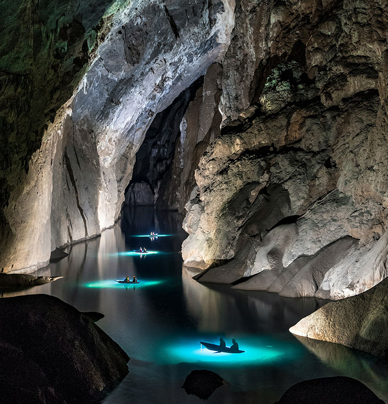 Small boats glide across the underground river inside Sơn Đoòng Cave in Quang Binh Province, Vietnam.
