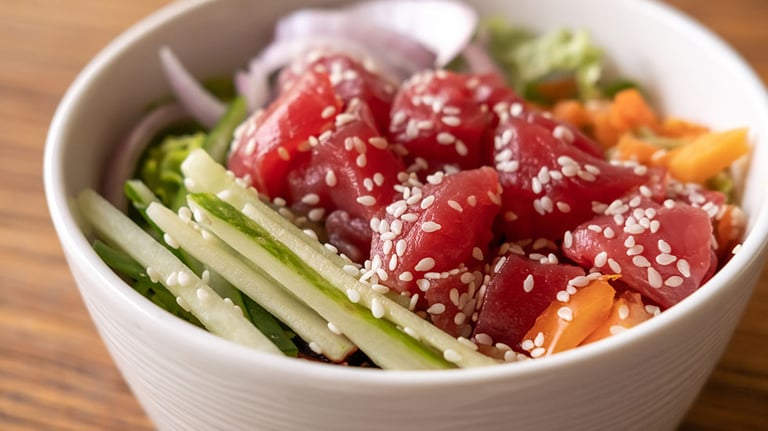 Healthy organic raw tuna Hawaiian poke bowl with cucumber, rice, carrots, onion served in bowl on wooden table. Photo courtesy Space_Cat/iStock.com