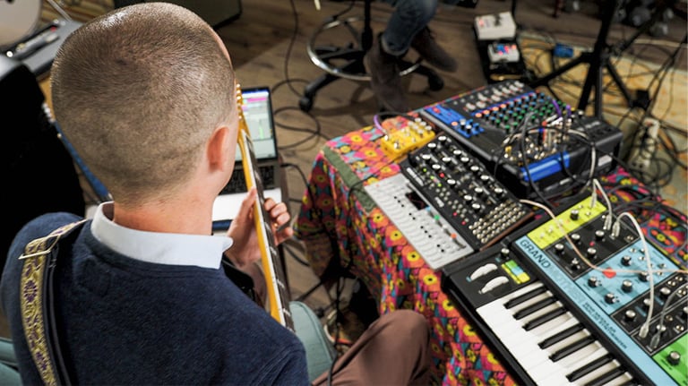 man in studio with electric keyboards and guitar