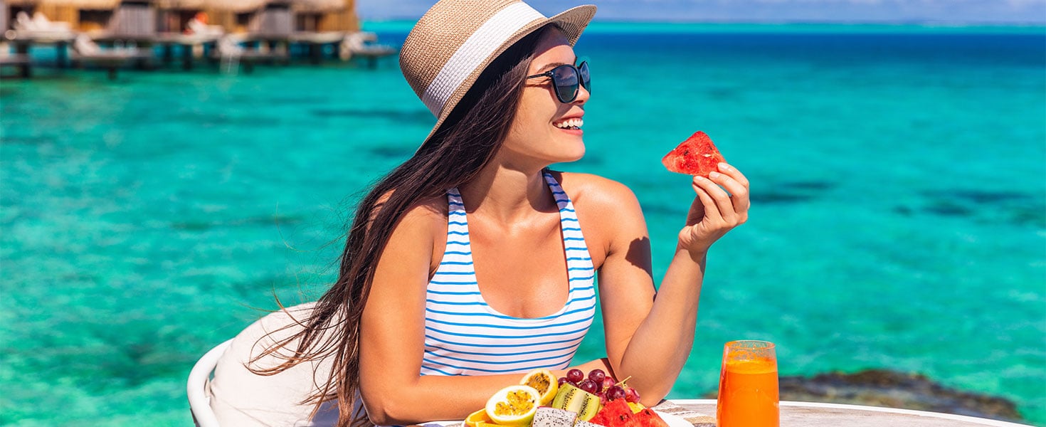 woman eating fruit in front of blue waters