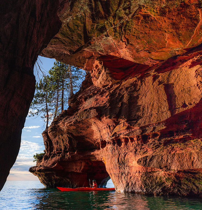 A lone kayaker exits a sea cave on The Apostle Island National Lakeshore in Wisconsin in Fall; Credit: timothy mattimore