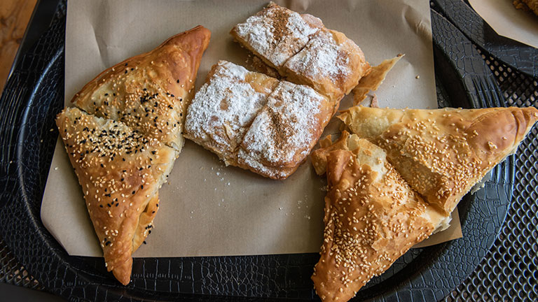 Plate of traditional spanakopita, bougatsa and tiropita pies in Rhodes, Greece; Credit:AlizadaStudios