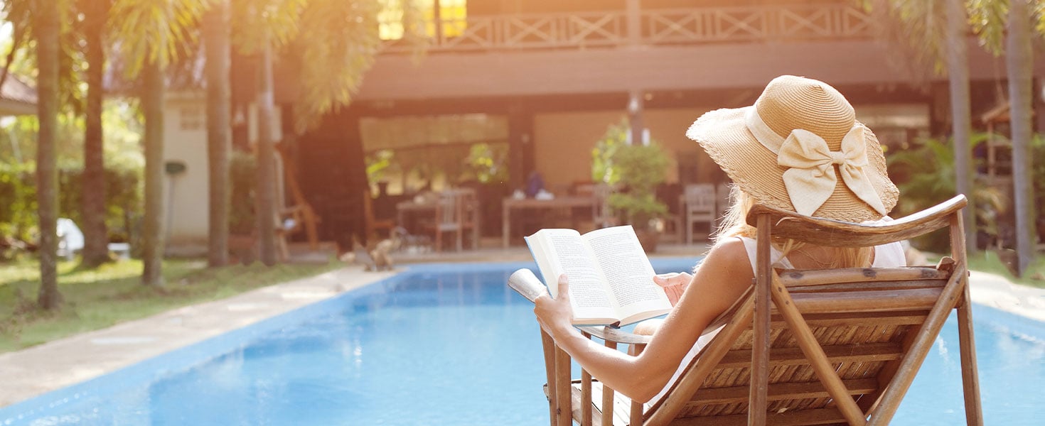 woman reading book in front of pool