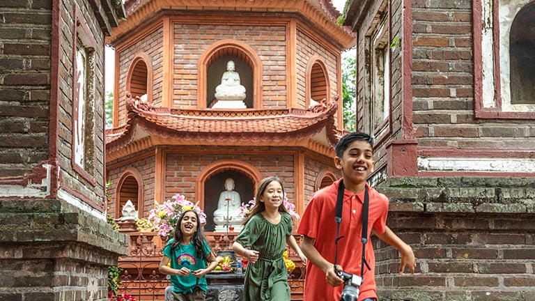 Children running and laughing near Tran Quoc Pagoda in Hanoi, Vietnam