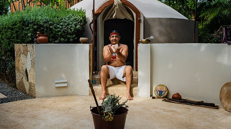 A shaman sits outside a traditional temazcal sweat lodge before leading a purification ceremony in Mexico.