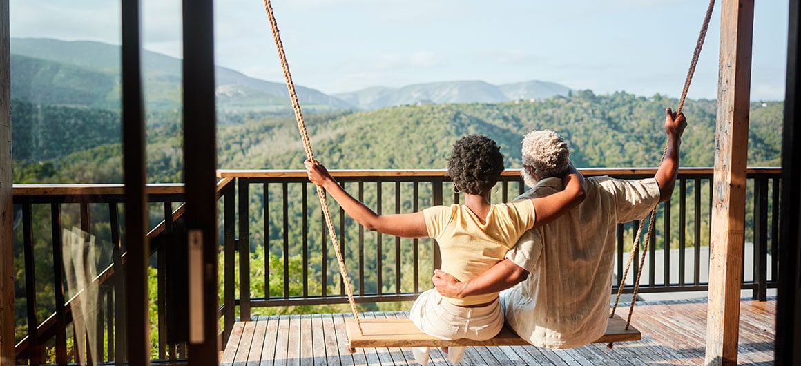Loving couple sitting on a balcony swing and looking at the scenic view; Credit: Goodboy Picture Company