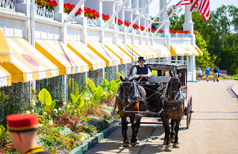Horse drawn carriage walks past Grand Hotel on Mackinac Island