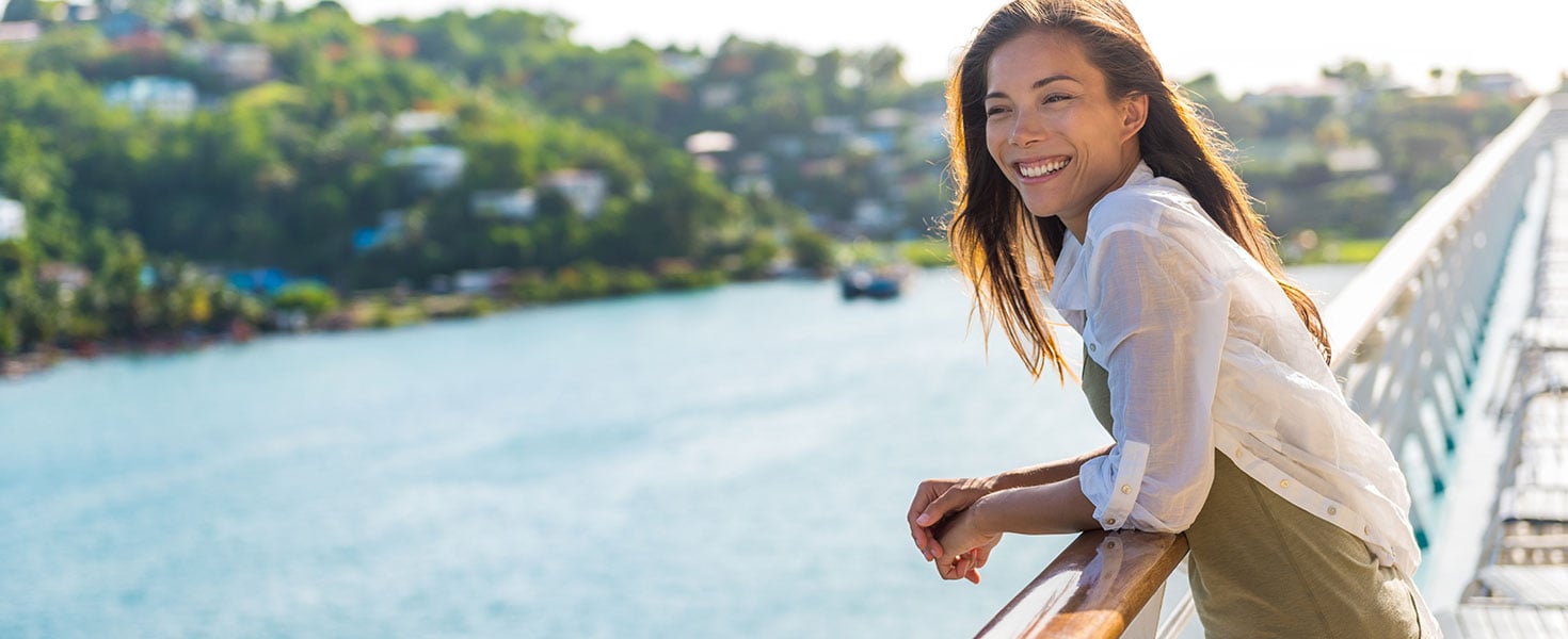 Cruise ship vacation Asian woman relaxing on deck enjoying view from boat of port of call city on St. Lucia island in the Caribbean. Happy casual tourist girl outside on tropical holiday destination; by Maridav