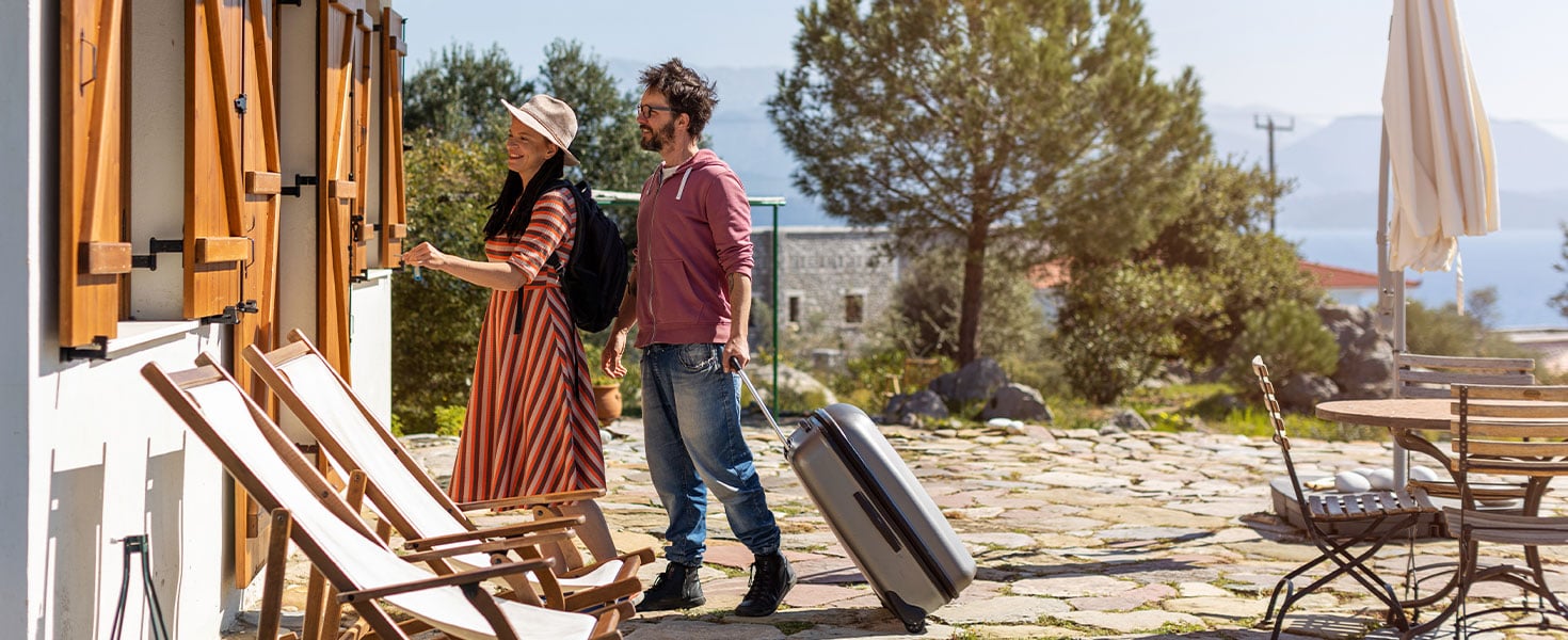 man and woman with luggage entering house