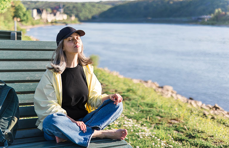 woman meditating on park bench with no shoes on