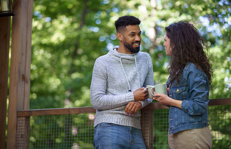 man and woman talking outside holding cups of coffee