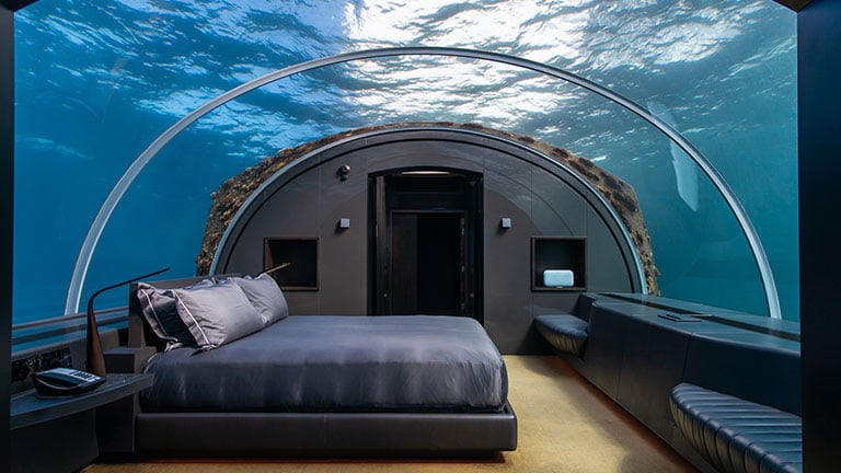 Luxury underwater hotel suite bedroom in Maldives island resort hotel with space underwater below lagoon surface in submerged glass dome Credit:MelanieMaya