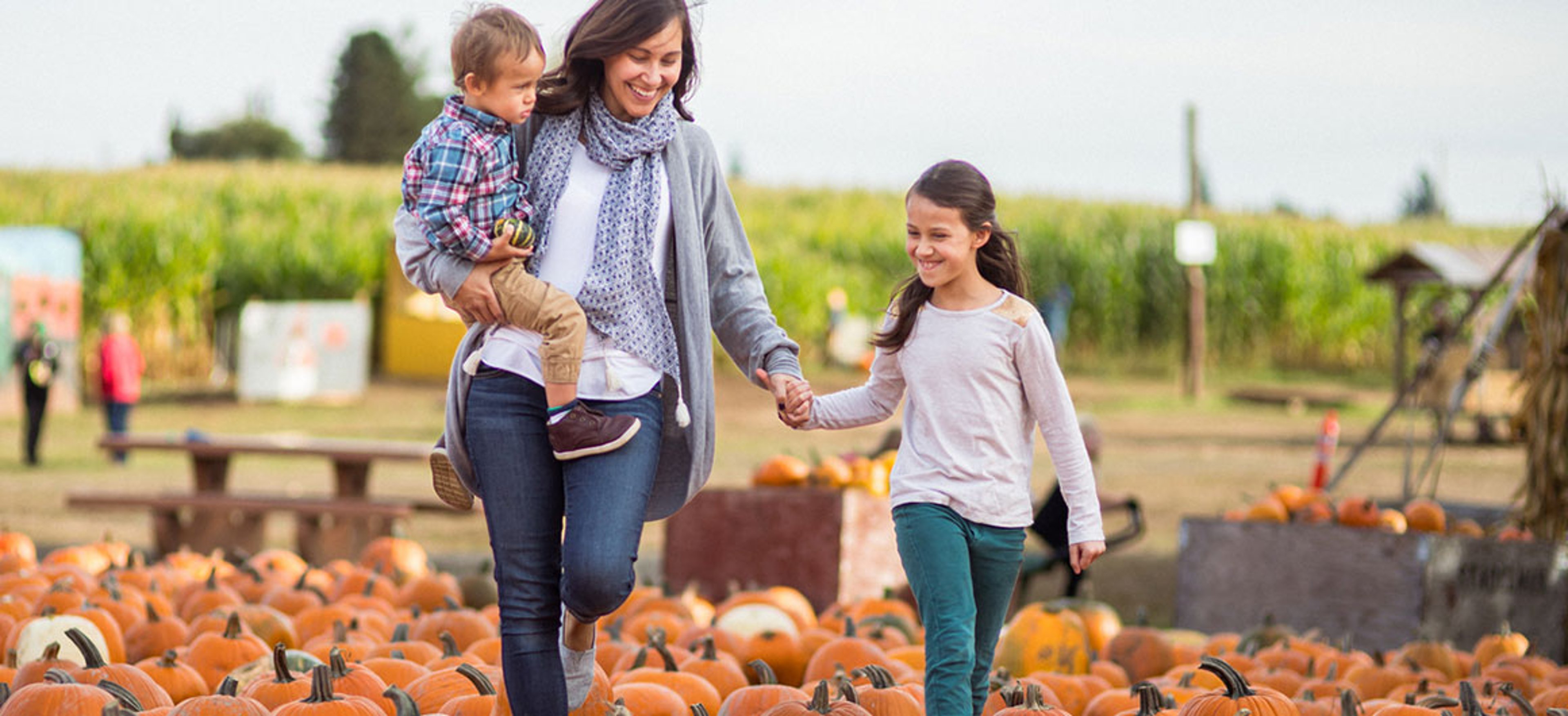 A mother and her children explore a pumpkin patch on an autumn day; photo courtesy of iStock. photo by Fly View Productions/iStock.com