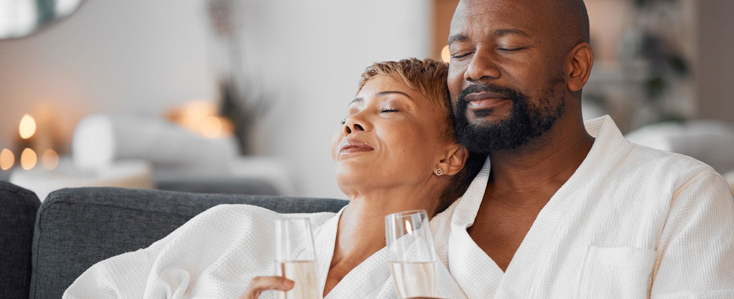 middle aged couple, cuddled in bath robes, drinking champagne
