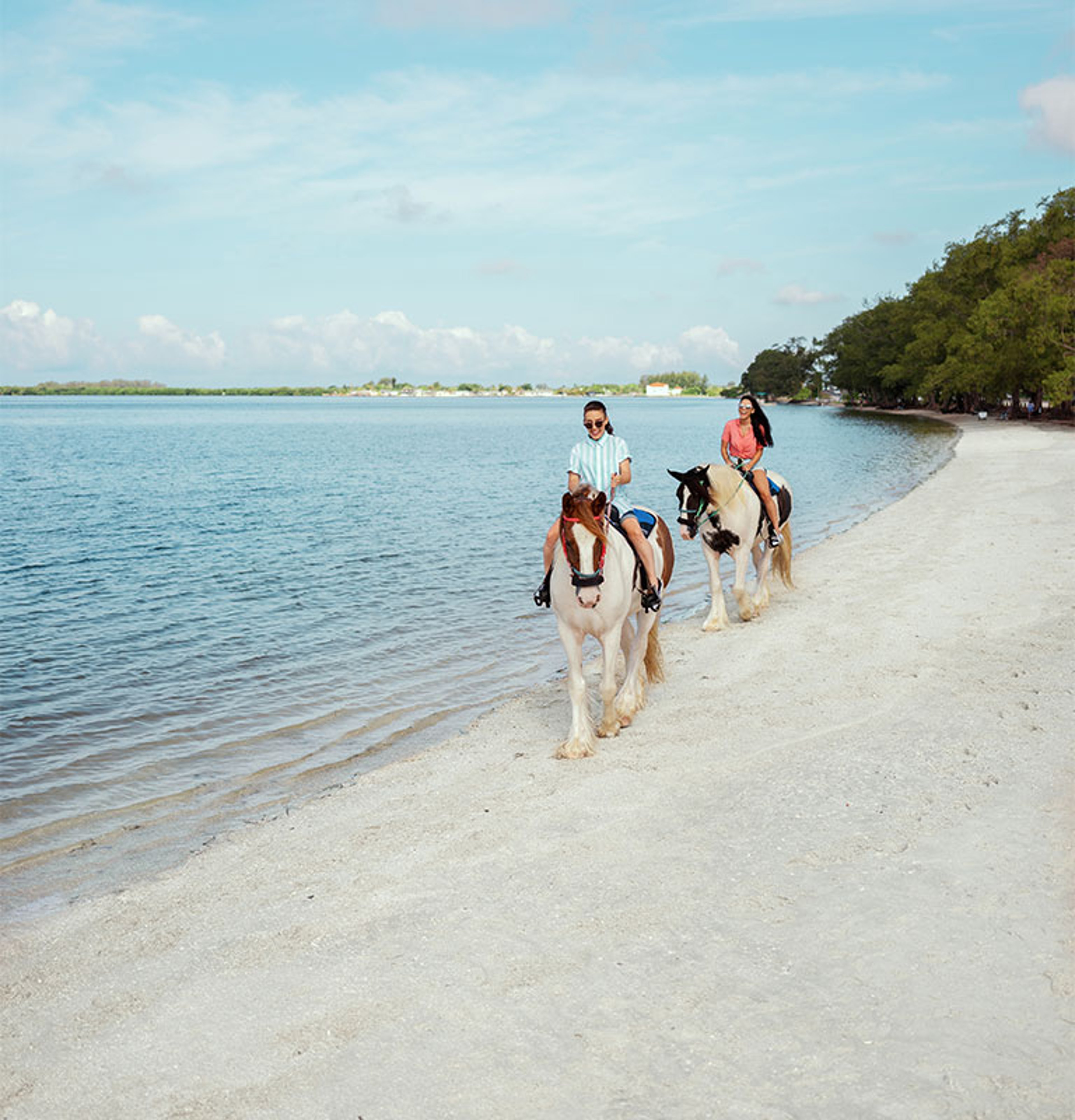 Anna Maria Island Wide shot of couple riding horses along the beach
