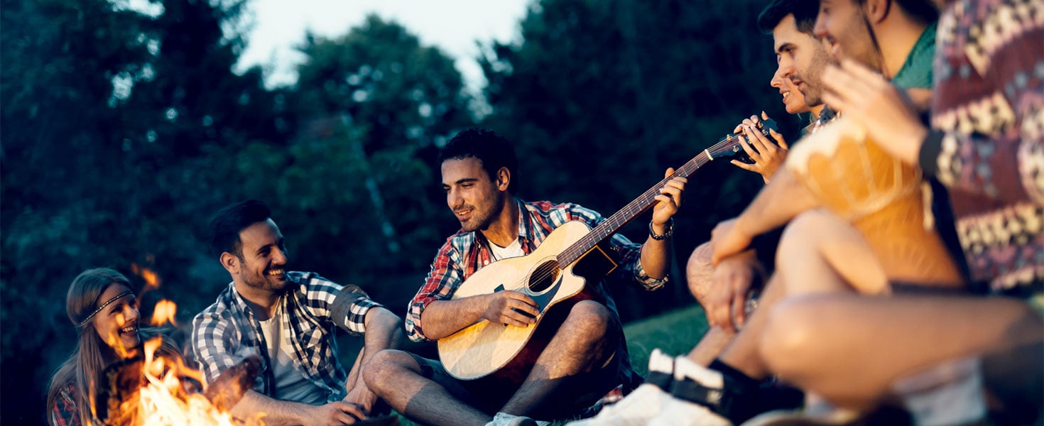 Friends enjoying music at campfire