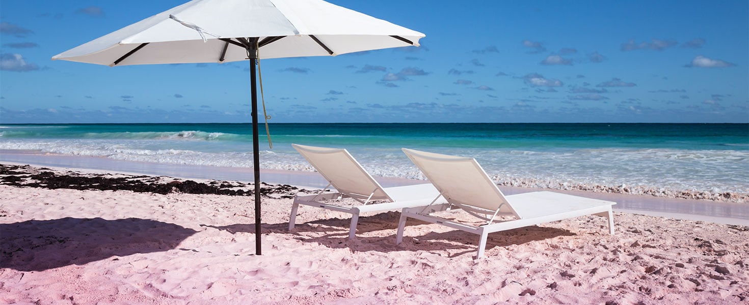white chairs and umbrella on a pink sand beach