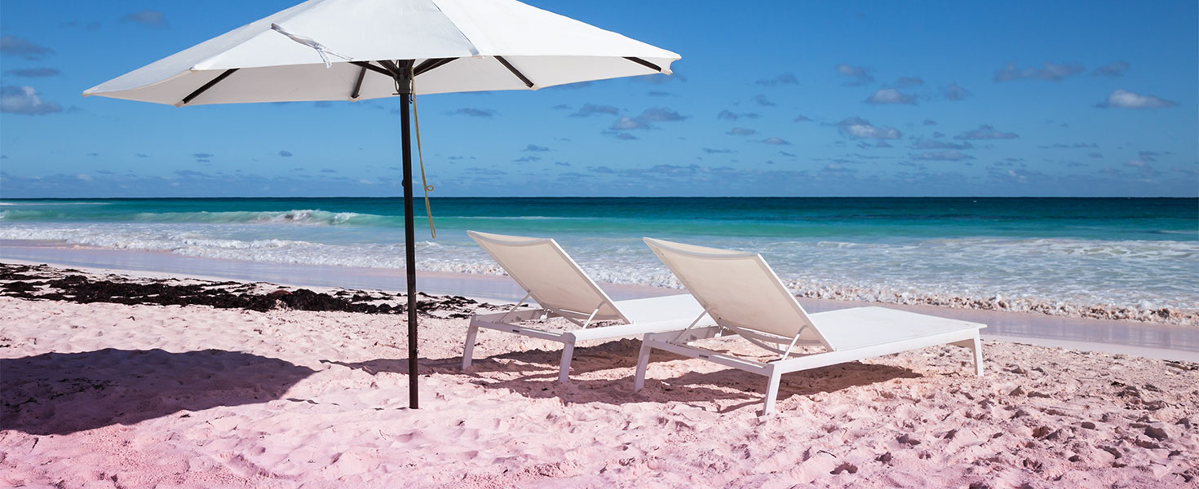white chairs and umbrella on a pink sand beach