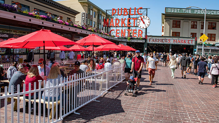 Visitors walking through Pike Place Market in Seattle on a sunny day.