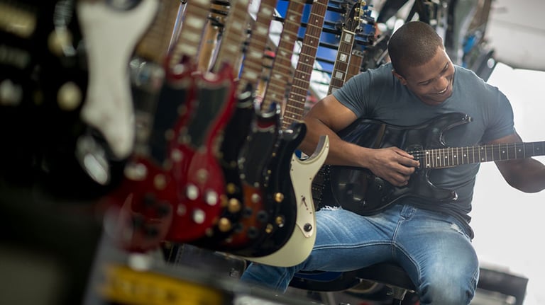 Man playing the guitar at a music store. Credit: andresr
