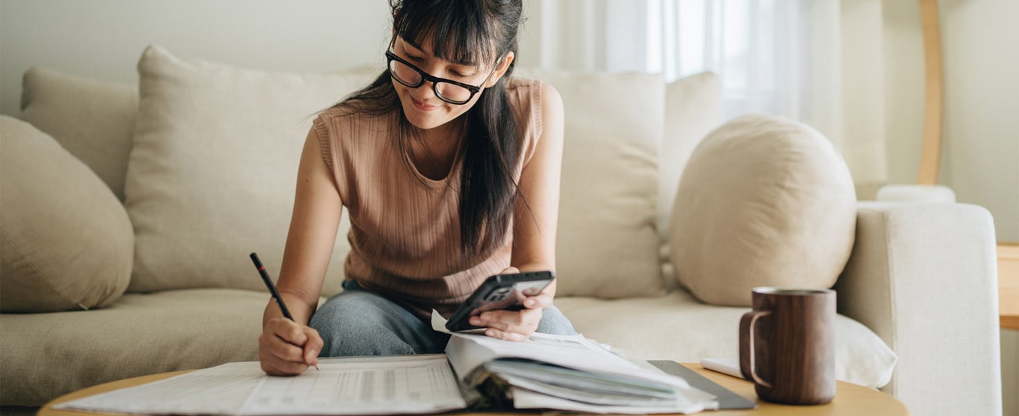 Woman with glasses, budgeting while sitting on couch