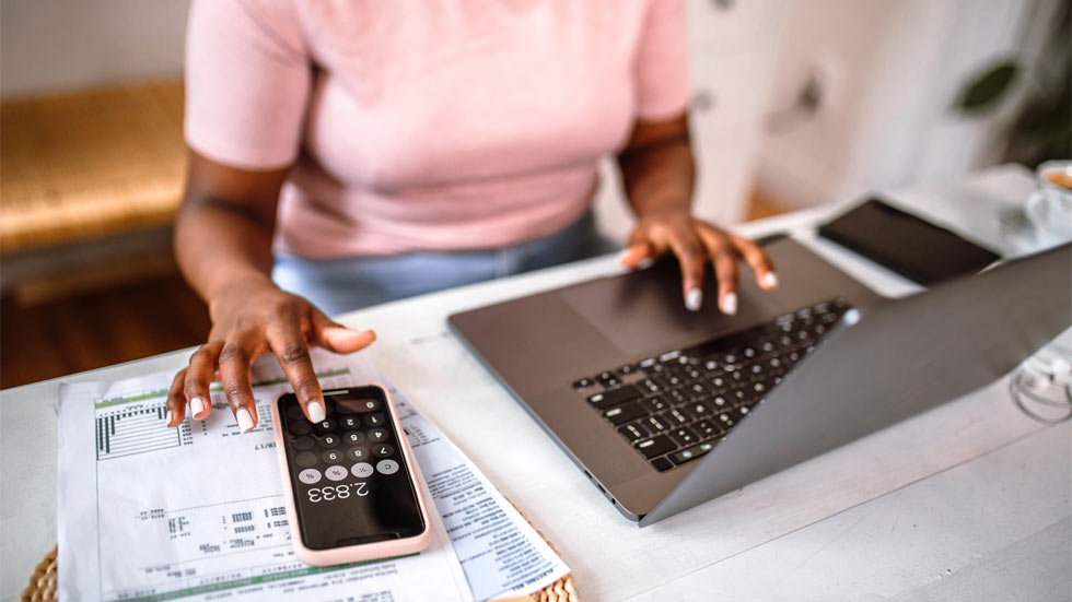 Hands of a woman typing on computer and calculator