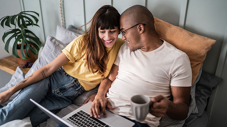 Young couple using the laptop in the bed at home Credit:FG Trade